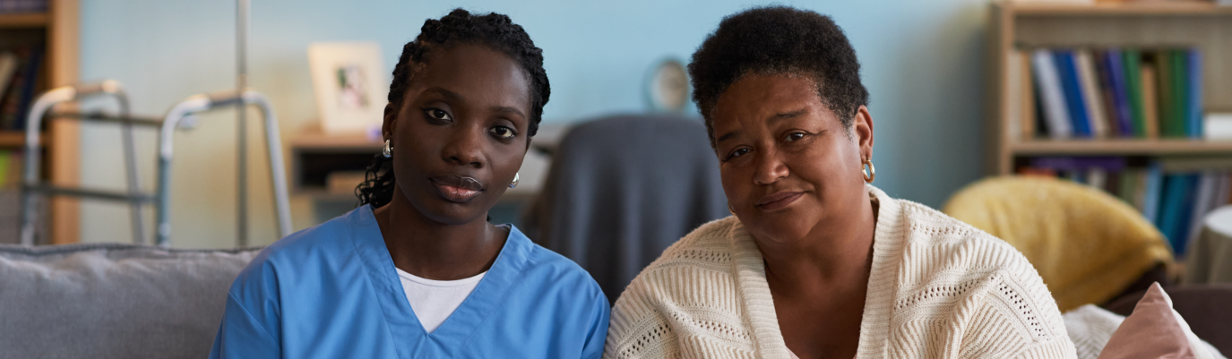 Caregiver and woman smiling together at home.