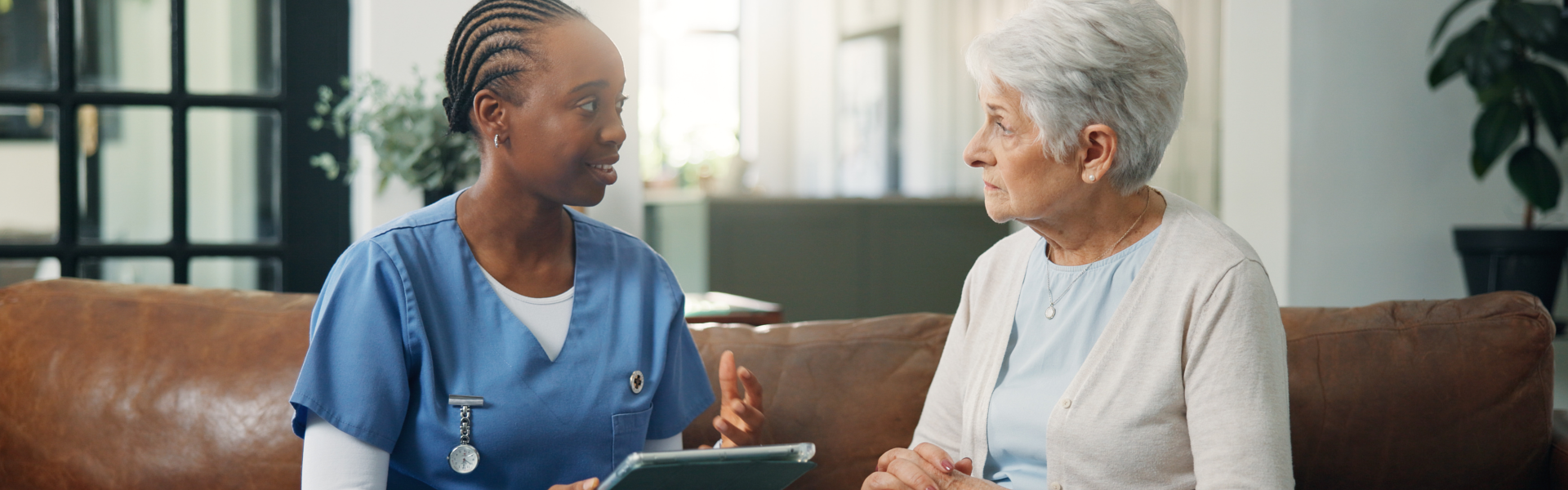 Caregiver talking with an elderly woman at home.