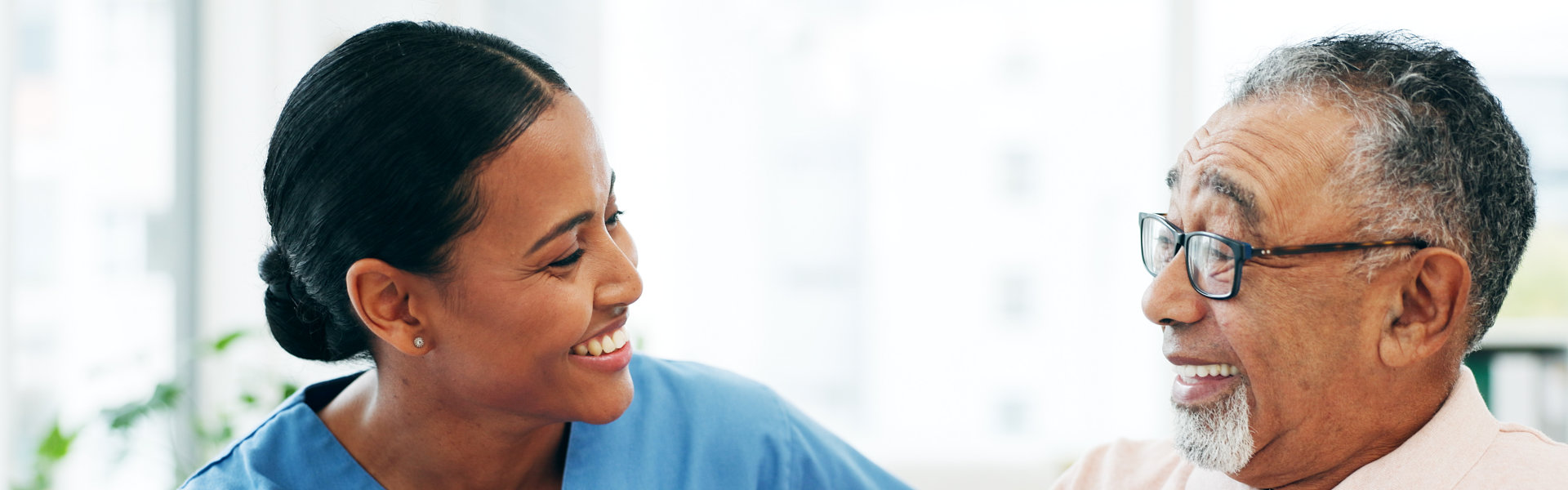 A smiling healthcare worker talking with an older man.